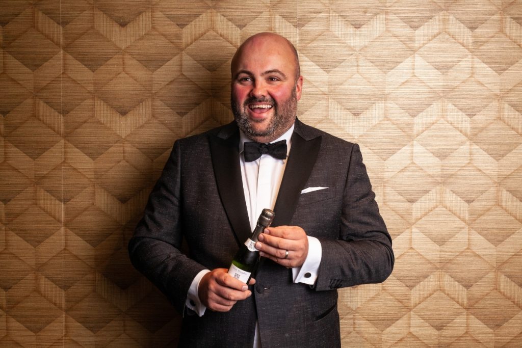 Smoking voor een goude muur met champagne